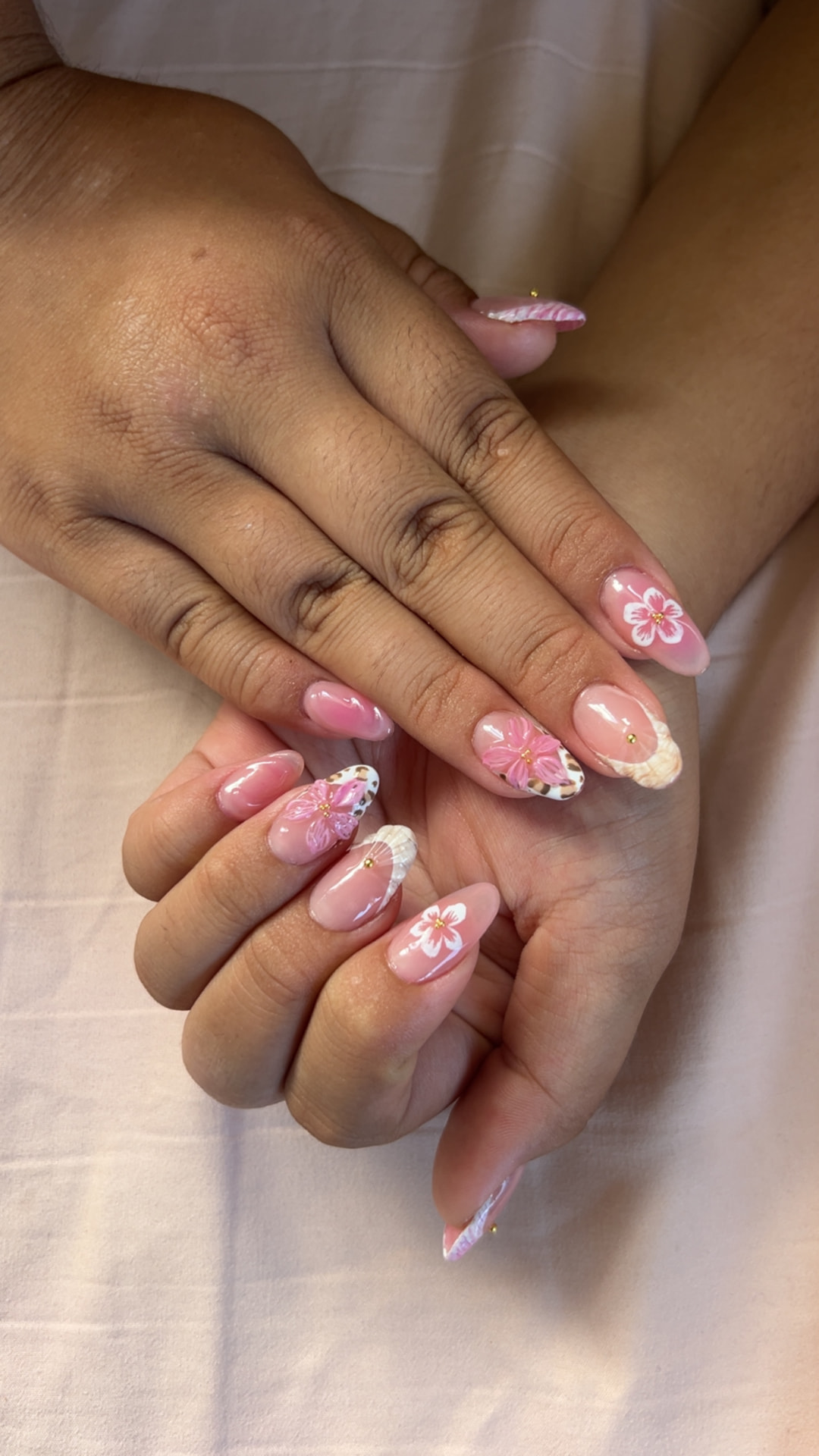 Pink almond nails with tropical flower art and shell-inspired French tips by Kulia