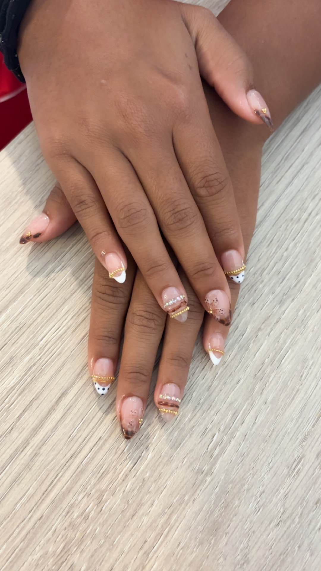 Neutral almond nails with white, tortoiseshell, and gold French details by Kulia